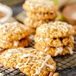 Apple Cinnamon Oatmeal Cookies stacked on a black wire rack with cinnamon sticks.