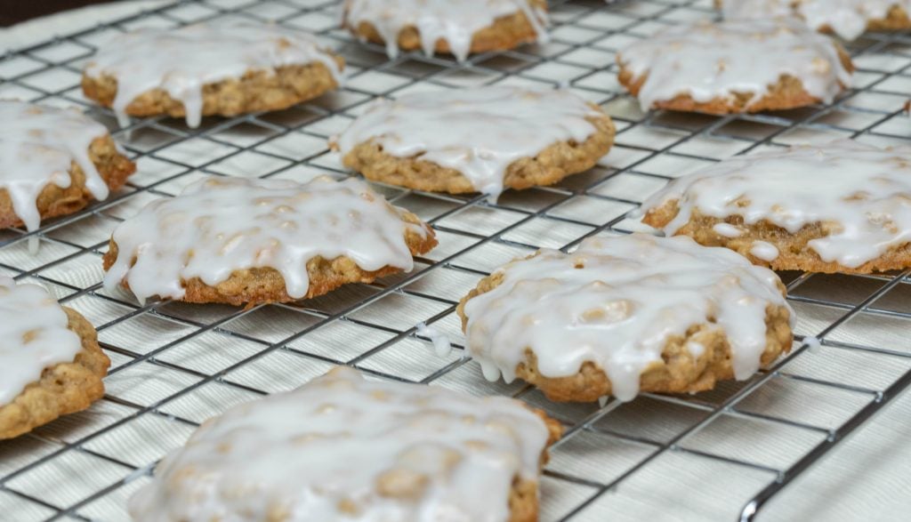 Glazed oatmeal cookies cooling on a wire rack.