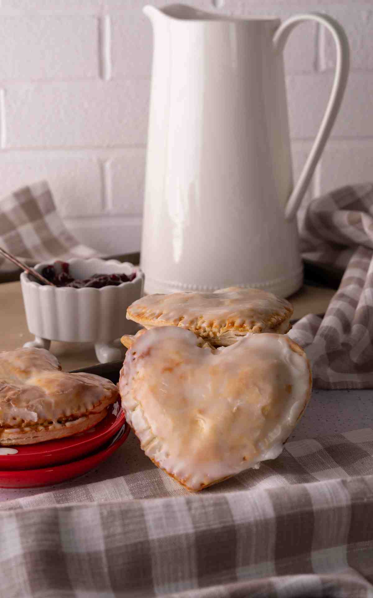 A heart shaped hand pie with cherry filling propped against more pies.