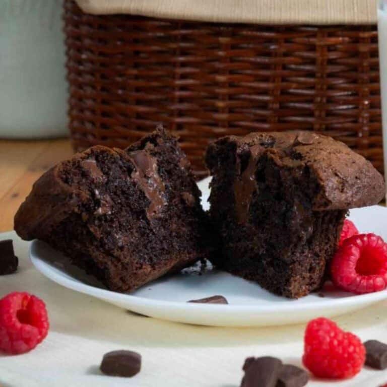 A Costco chocolate chunk muffin copycat cut in half with fresh raspberries.