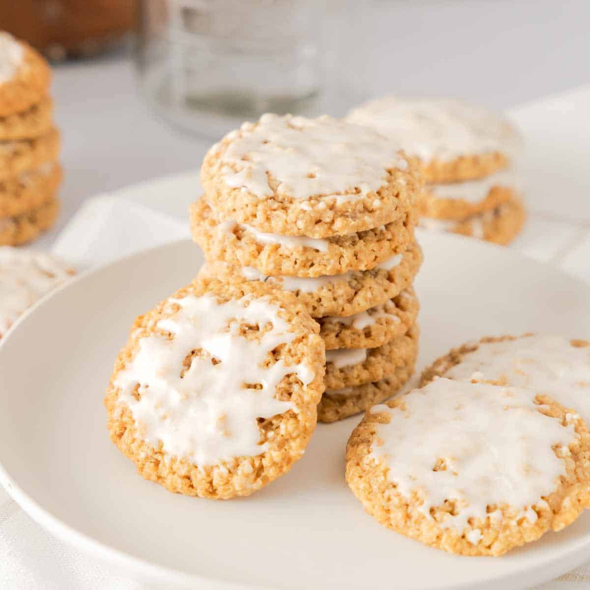 Old Fashioned Iced Oatmeal Cookies stacked and scattered on white plate.