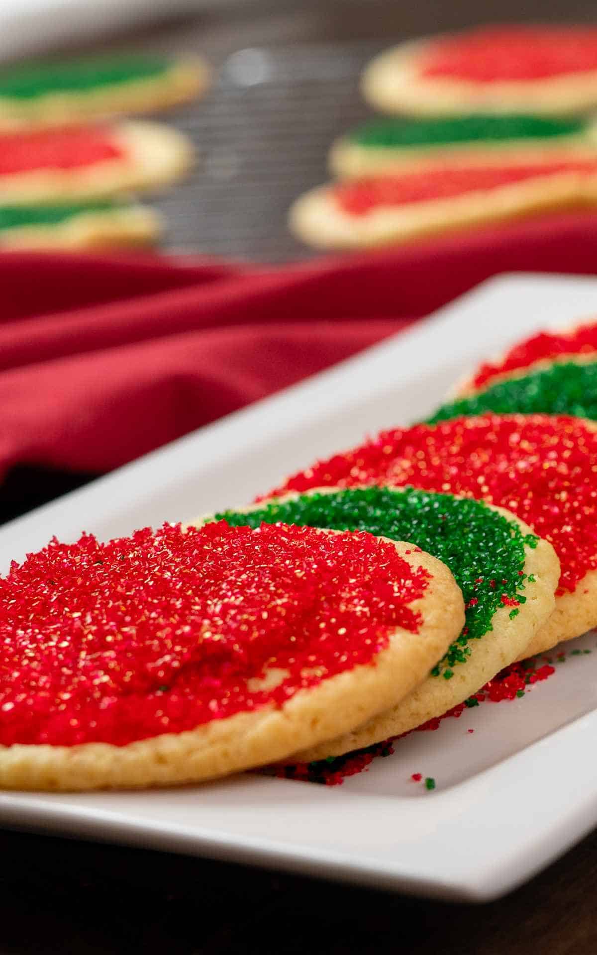 Close up of red and green colored sugar on round sugar cookies.