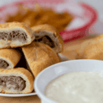 philly steak and cheese bombs with philly steak sauce in white bowl french fries