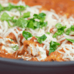 chicken and spinach skillet manicotti topped with cheese and diced spinach