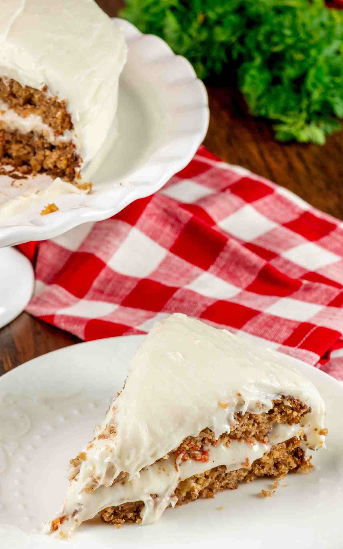 A slice of carrot cake taken from a classic layer cake on a plate.