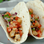 blackened chicken tacos with pineapple pico de gallo in tortillas on a gray plate