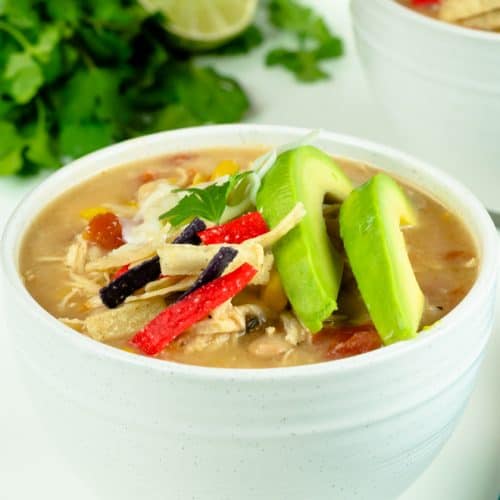 A bowl filled to the rim with white chicken chili and sliced avocado.