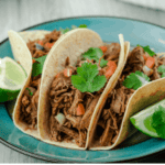 Instant Pot Beef Barbacoa Tacos served with pico de gallo, fresh sliced limes, and cilantro