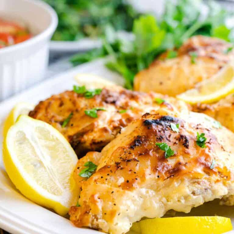 Air Fryer Lemon Pepper Chicken Breasts on a serving platter with sliced lemons.