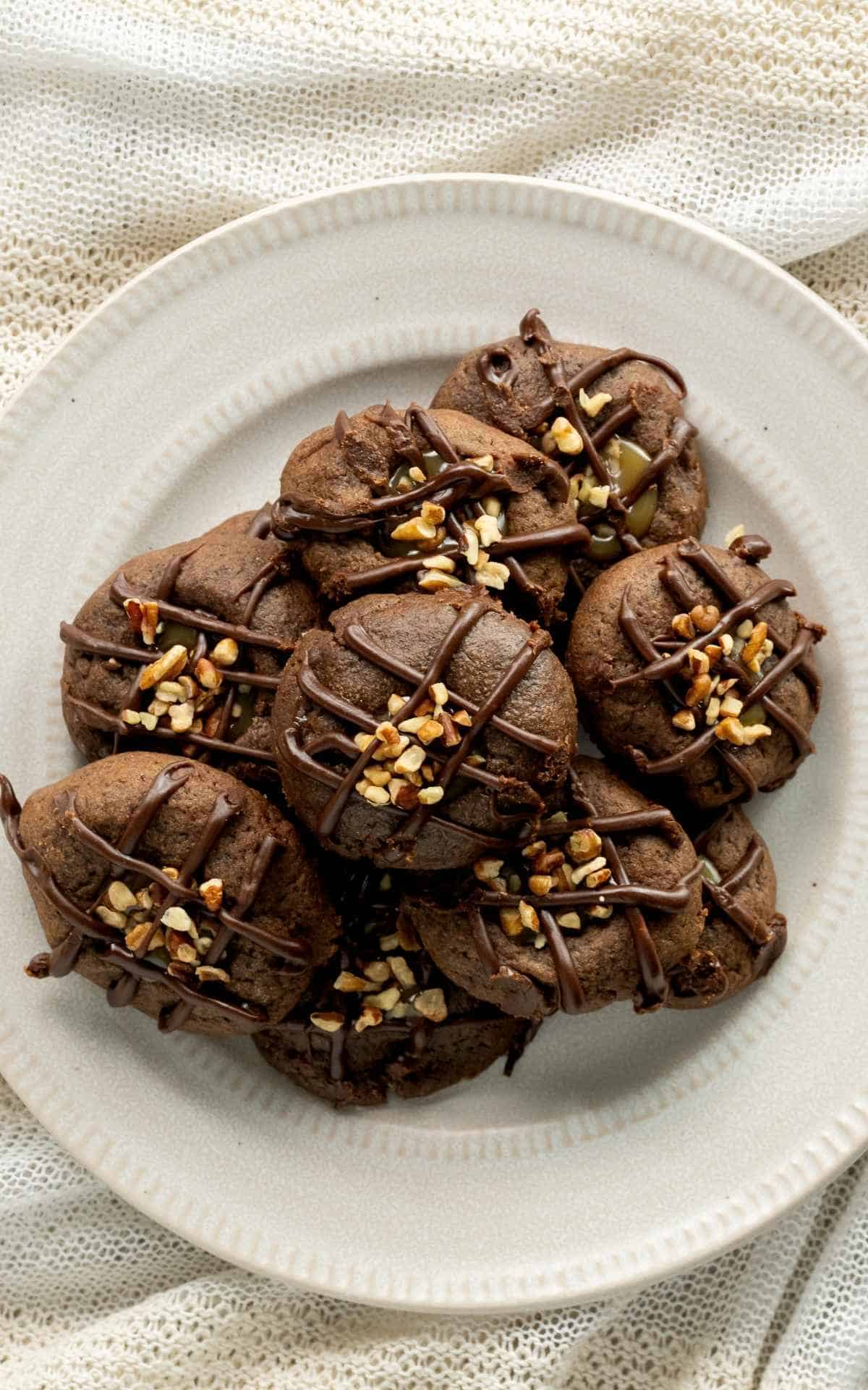 A plate of chocolate thumbprint cookies with chocolate drizzle.