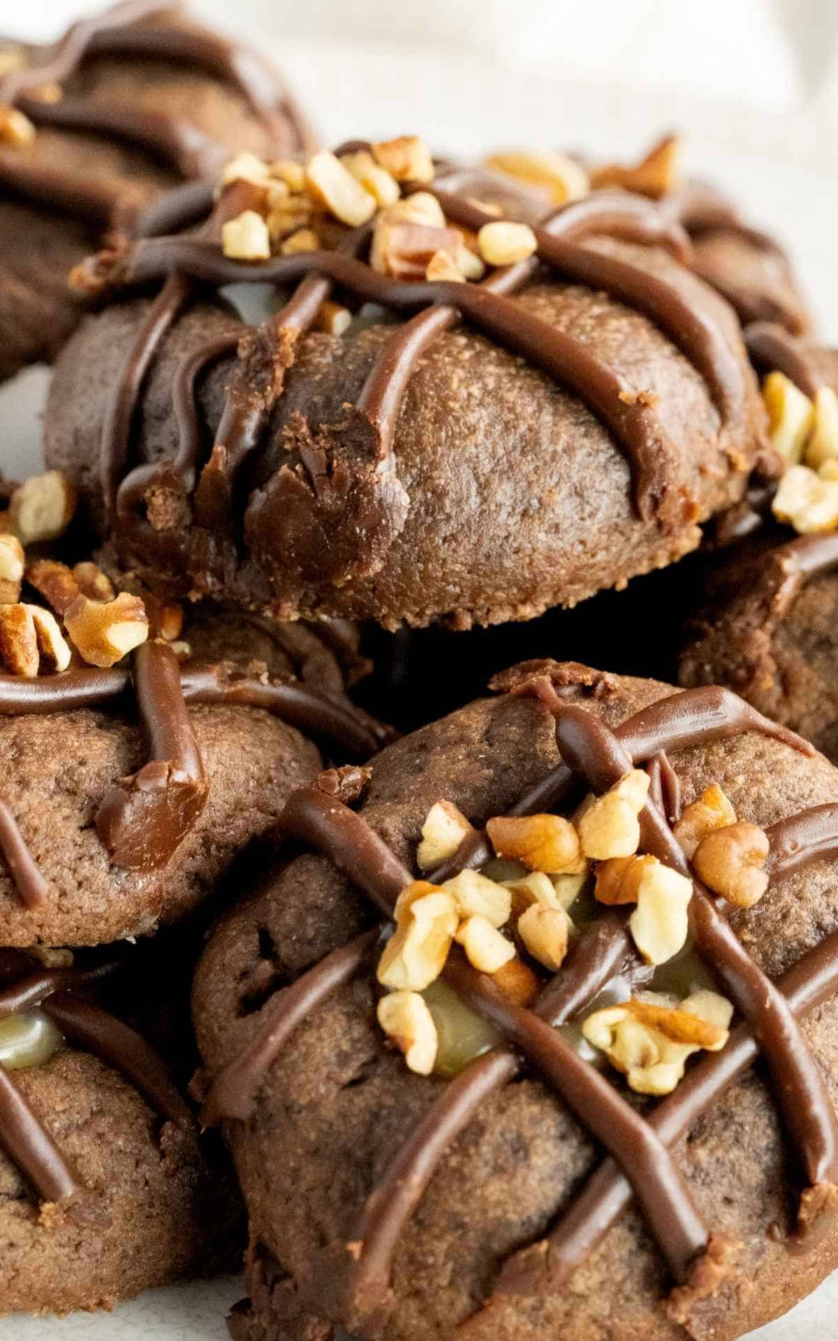 Close up of caramel filled chocolate thumbprint cookies with chopped pecans.