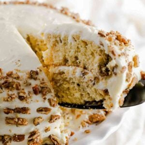 A slice of butter pecan cake being pulled from a decorated southern butter pecan cake.