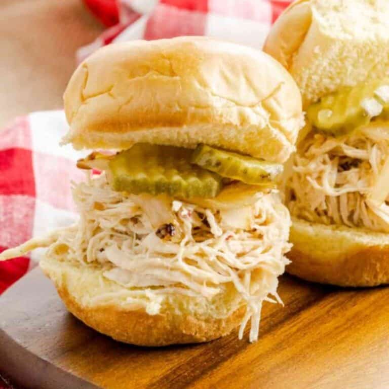 Carolina Style Vinegar Chicken Sandwiches served with pickles on a wooden board.