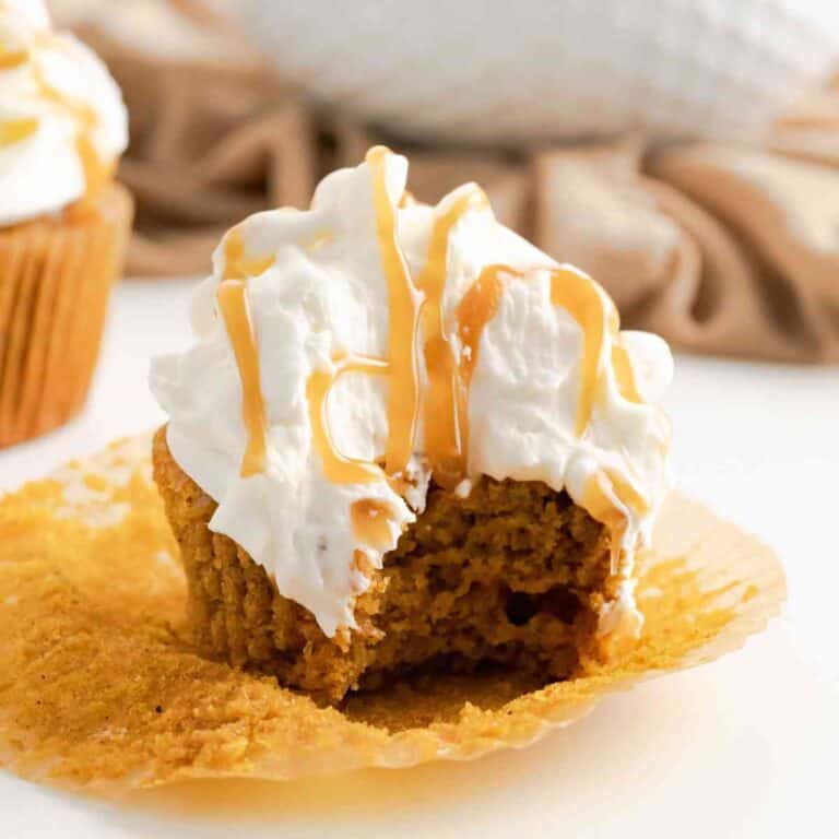 Pumpkin Spice Latte Cupcakes with a bite taken out of one that is drizzled with caramel.