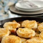 Turkey pot pie in cast iron skillet topped with biscuits.