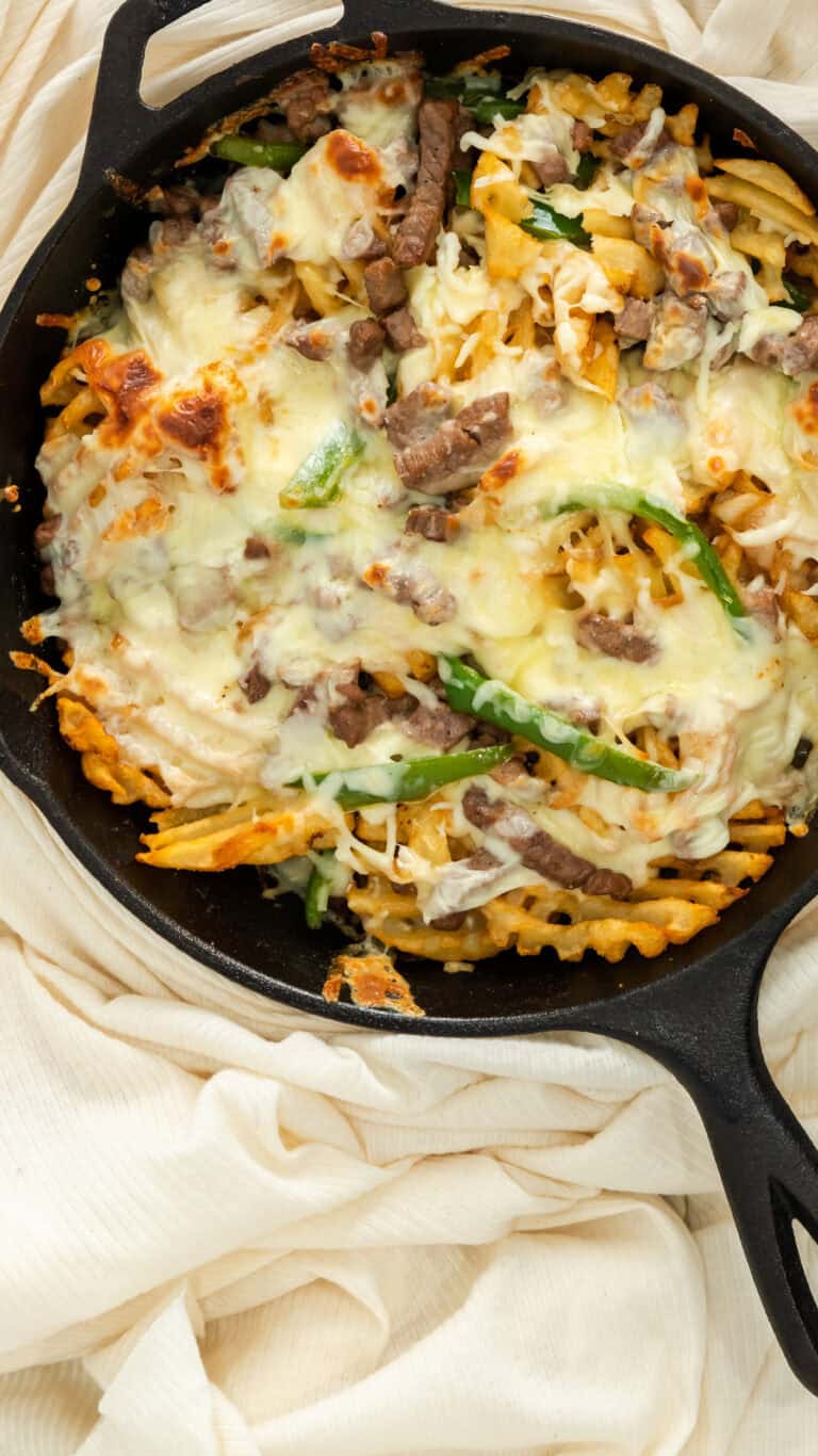 close up of Philly steak and cheese fries in cast iron skillet