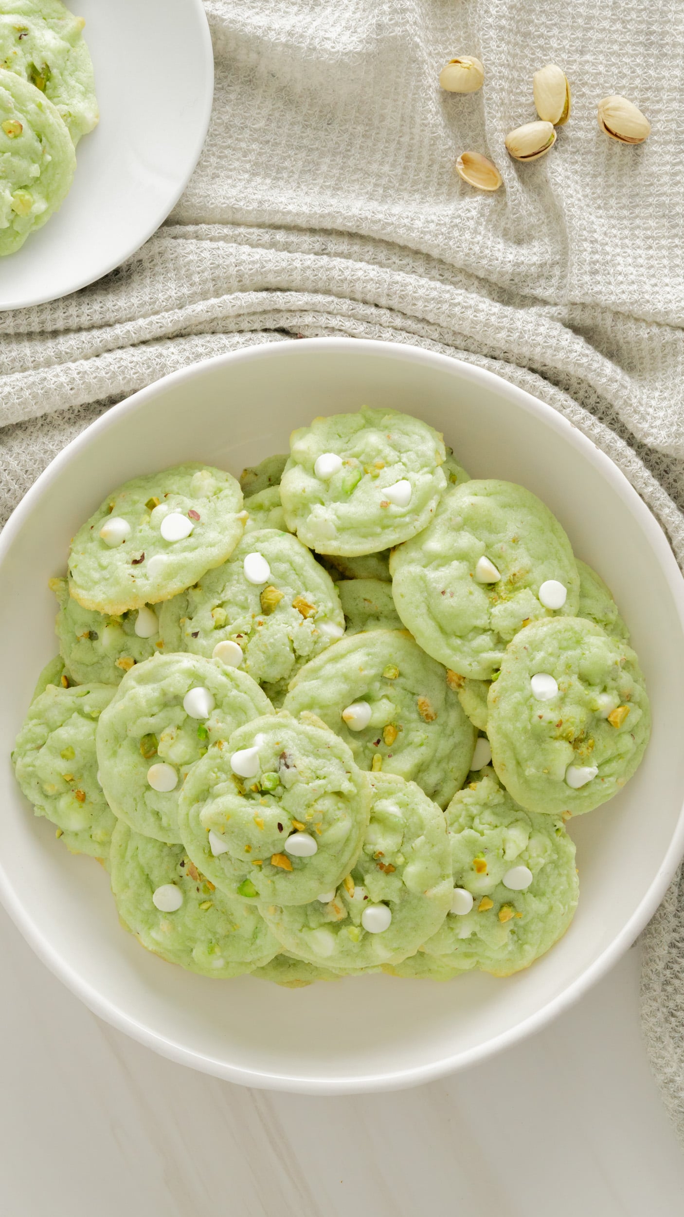 Top view of pistachio cookies in white serving platter with gray background. 