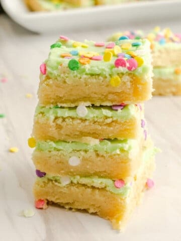 four sugar cookie bars stacked with green icing and colorful sprinkles