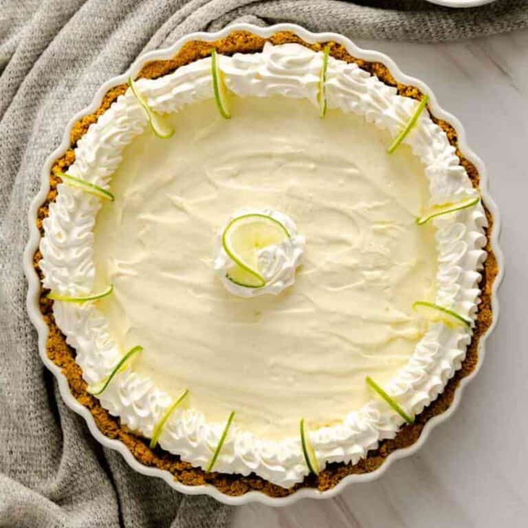 No Bake Key Lime Pie decorated with cool whip and sliced key limes.