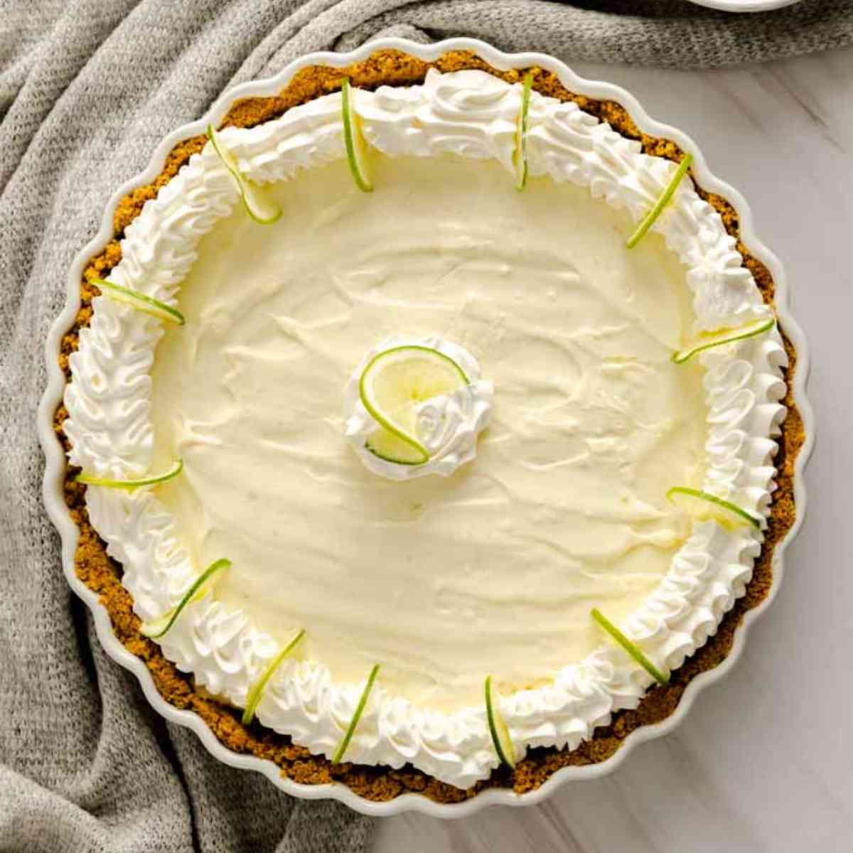 No Bake Key Lime Pie decorated with cool whip and sliced key limes.