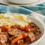 Instant Pot Beef Bourguignon with mashed potatoes in a white bowl.