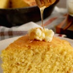 A slice of skillet buttermilk cornbread with a dallop of whipped butter and drizzled with local honey.