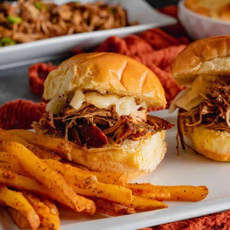 Two Instant Pot Jerk Chicken Sandwiches on a white serving plate with fries.