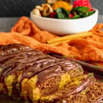 Sliced marble cake topped with ganache on dark pan.