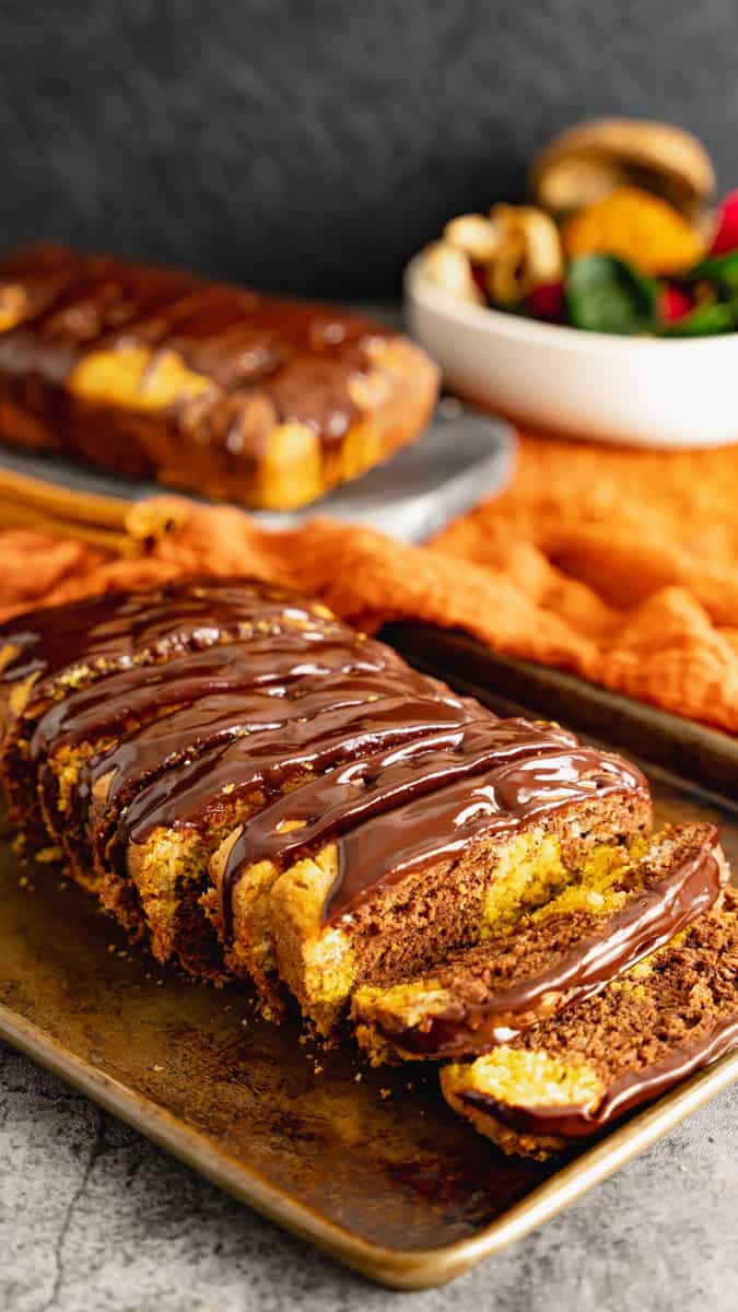 Chocolate pumpkin marble cake sliced into thick slices and topped with chocolate ganache.