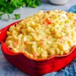 A casserole dish of Instant Pot Amish Macaroni Salad with bowls in the background.