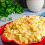 A casserole dish of Instant Pot Amish Macaroni Salad with bowls in the background.