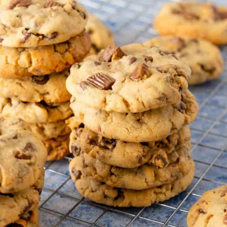 Thick Peanut Butter Cup Cookies that are stacked on a black cooling rack.