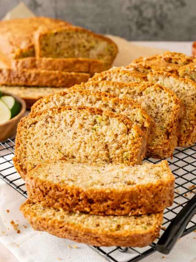 Thickly sliced banana zucchini bread with a sliced loaf in the background.