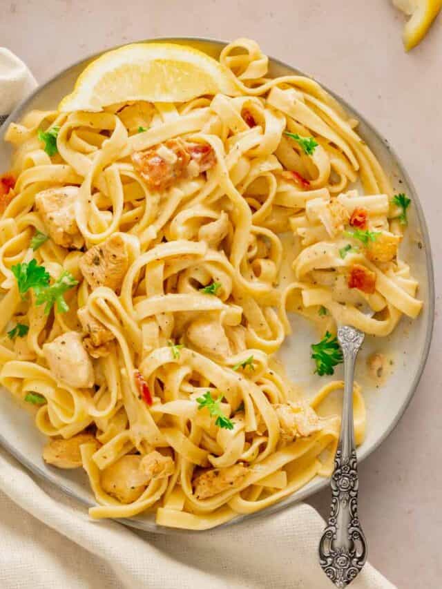 A plate with cajun seasoned chicken, crispy bacon, and fresh parsley tossed with fettuccine.