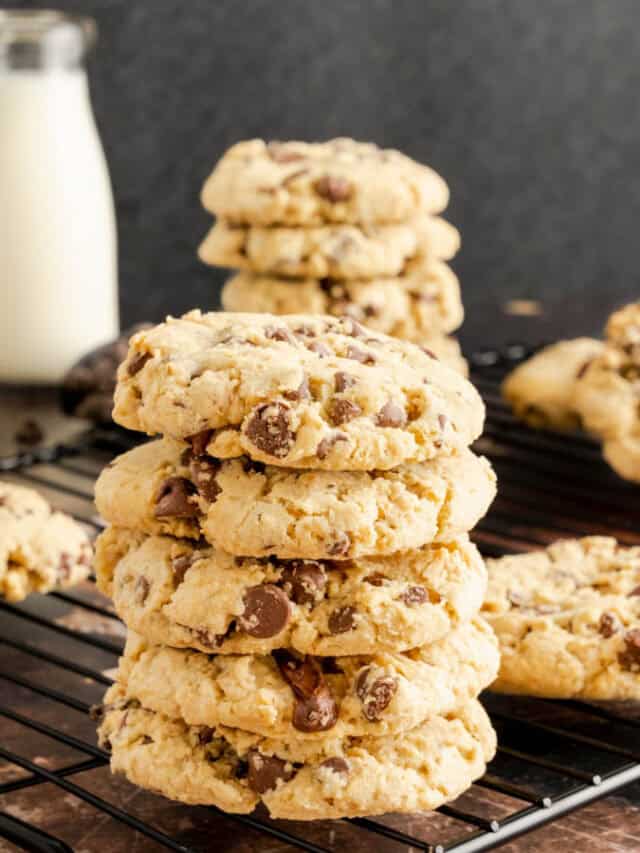A stack of oatmeal cookies with chocolate chips on a black wire rack.