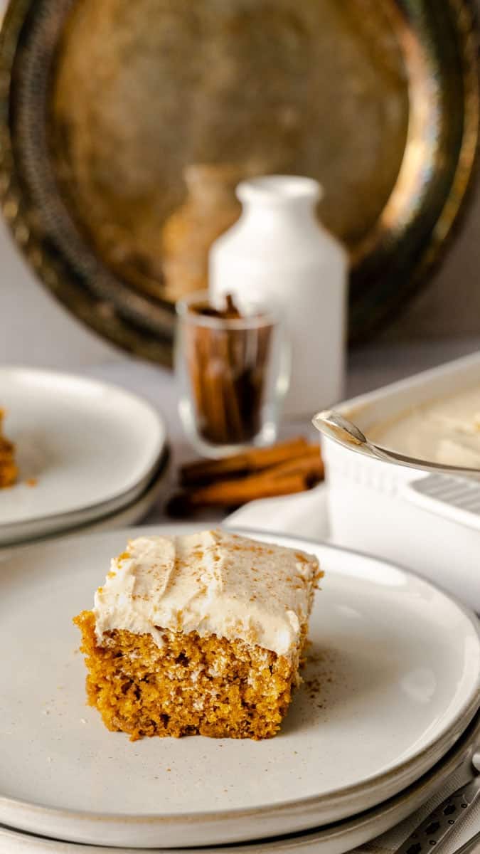 A slice of pumpkin cake with spiced cream cheese frosting on a plate.