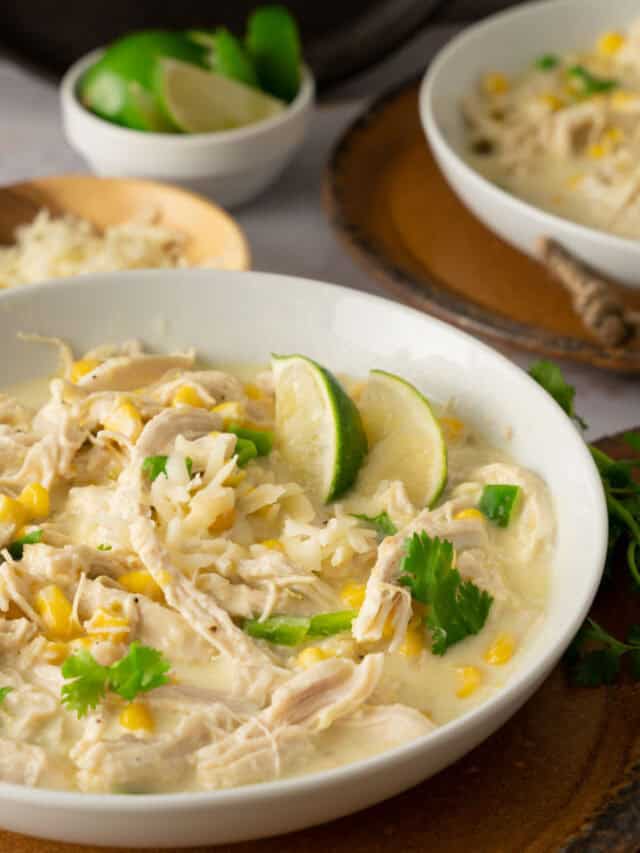 Instant Pot White Chicken Enchilada Soup in a white bowl with lime and cilantro.