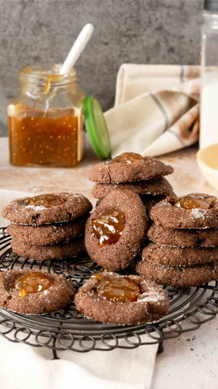 Stacks of fig chocolate thumbprint cookies on a black cooling rack.