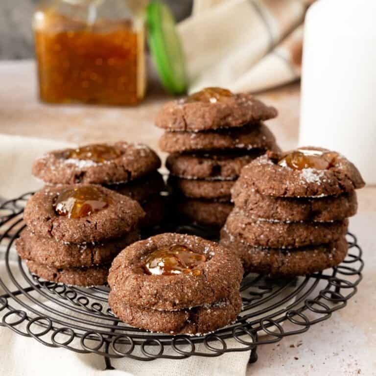 A stack of fig chocolate thumbprint cookies on a wire rack.