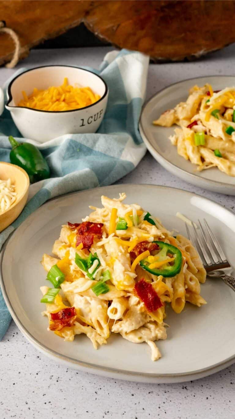 A plate of Instant Pot Jalapeno Popper Chicken Pasta garnished with bacon and scallions.