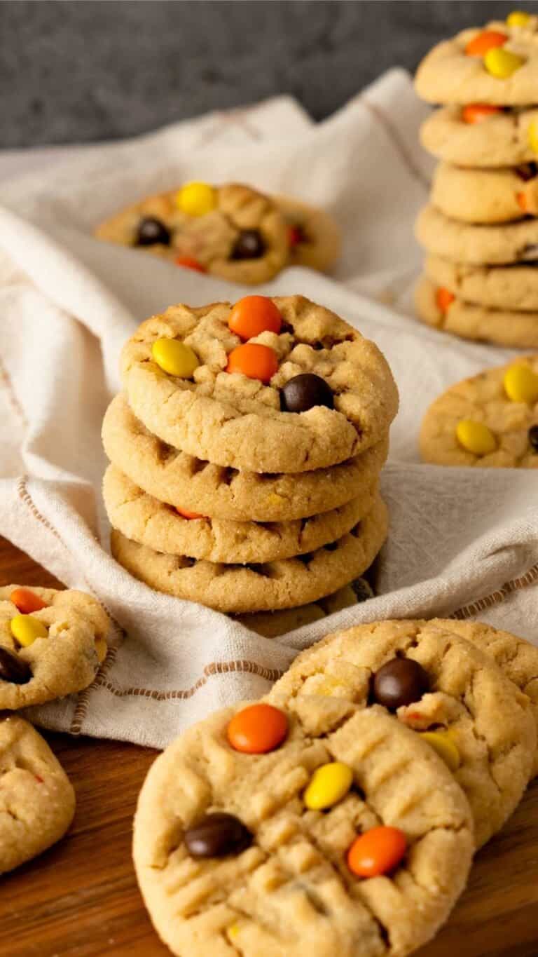 Reese Piece's Peanut Butter cookies stacked on a brown linen.