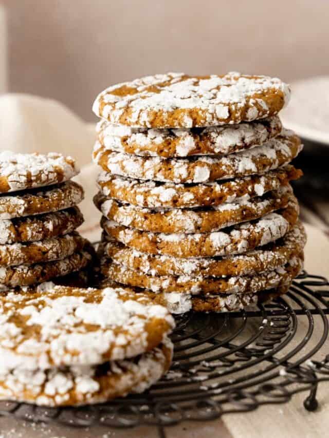 Stacks of crinkle gingerbread cookies on a decorated round wire rack.