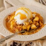 Old fashioned apple crisp with a scoop of ice cream and caramel sauce.
