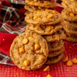 A stack of butterscotch gingerbread cookies on a red cookie sheet with Christmas plaid in the background.