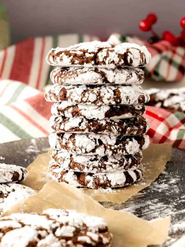 A stack of hot cocoa crinkle cookies with a Christmas background.