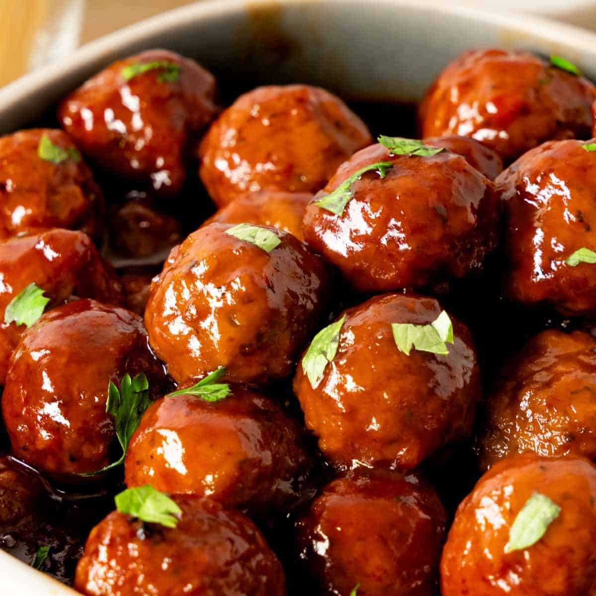 Close up of Instant Pot Grape Jelly Meatballs in a stoneware bowl.