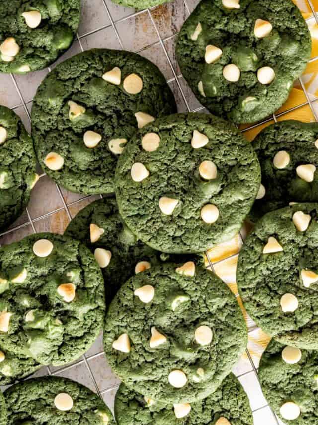 Birds eye view of white chocolate chip green velvet cookies on a patterned yellow napkin.