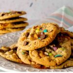 A plate of Easter Trash Cookies on a platter with M&M's, caramels, and pretzel mix-ins.