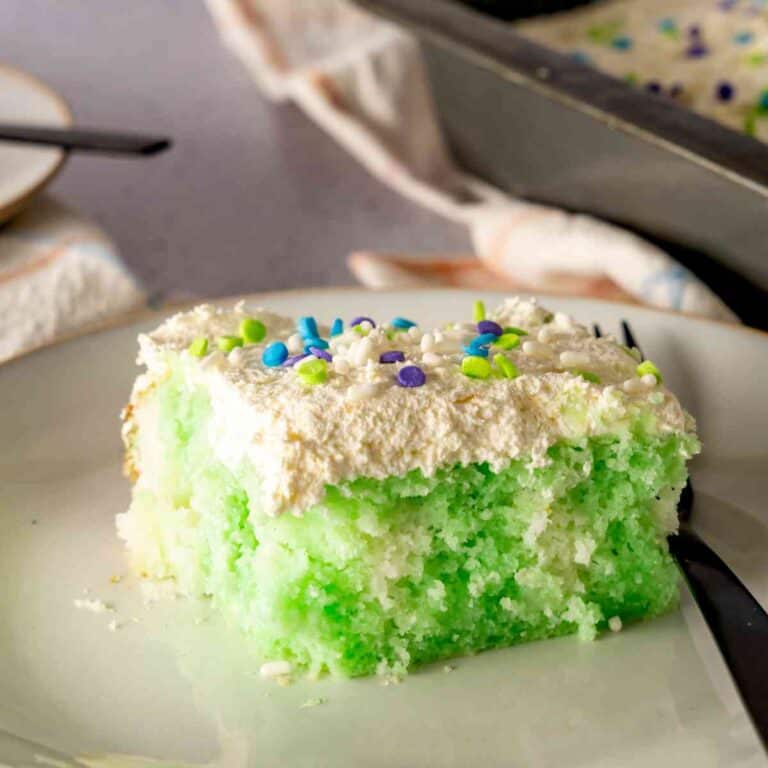 A slice Lime Poke Cake decorated with spring sprinkles.