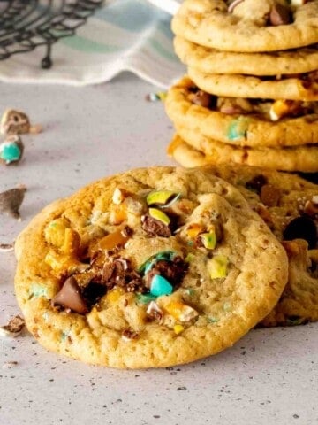 A stack of Easter trash cookies with M&M's, caramels, pretzels, and chocolate chips.